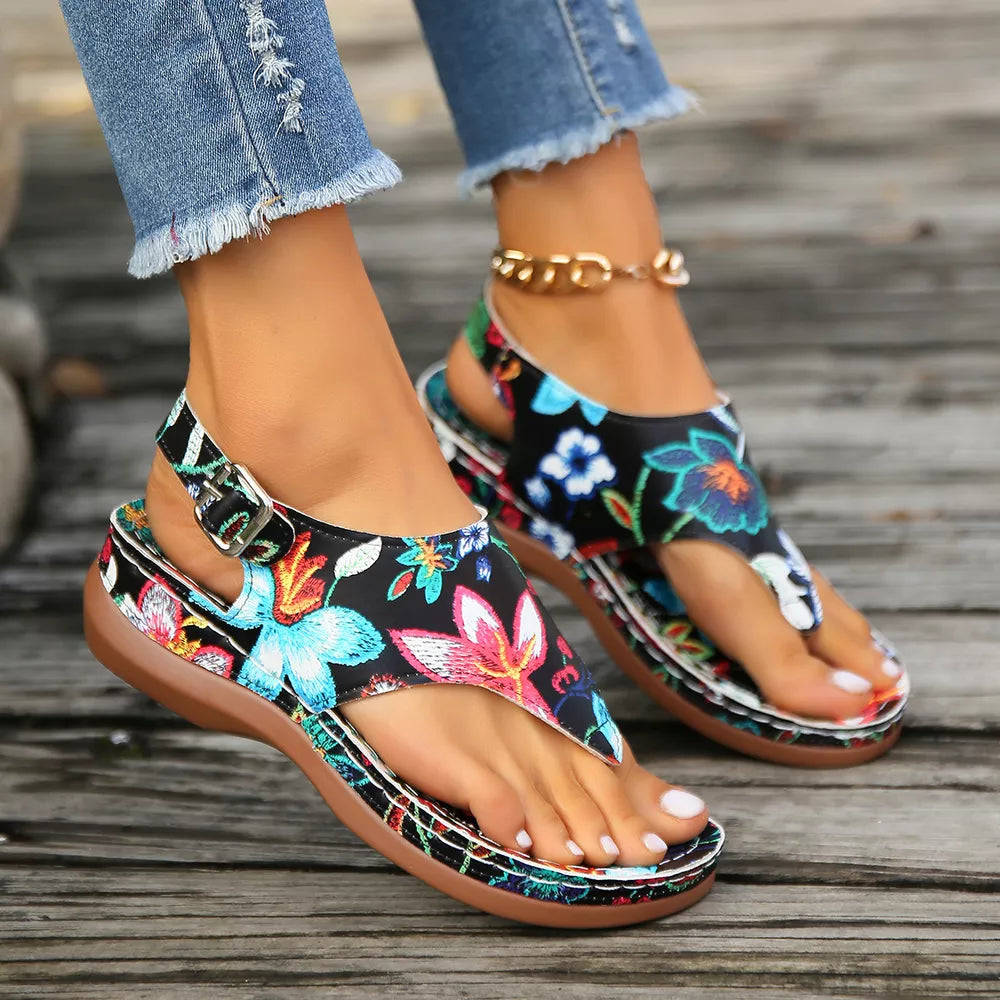 Embroidered floral thong wedge sandals with adjustable ankle strap and buckle.