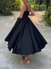 Black a-line midi dress with square neckline and full skirt, worn by a woman.