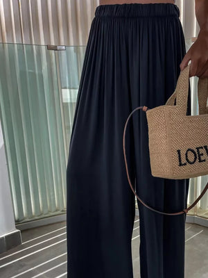 Dark blue maternity pants with paperbag waist and wide legs, styled with a straw tote bag.