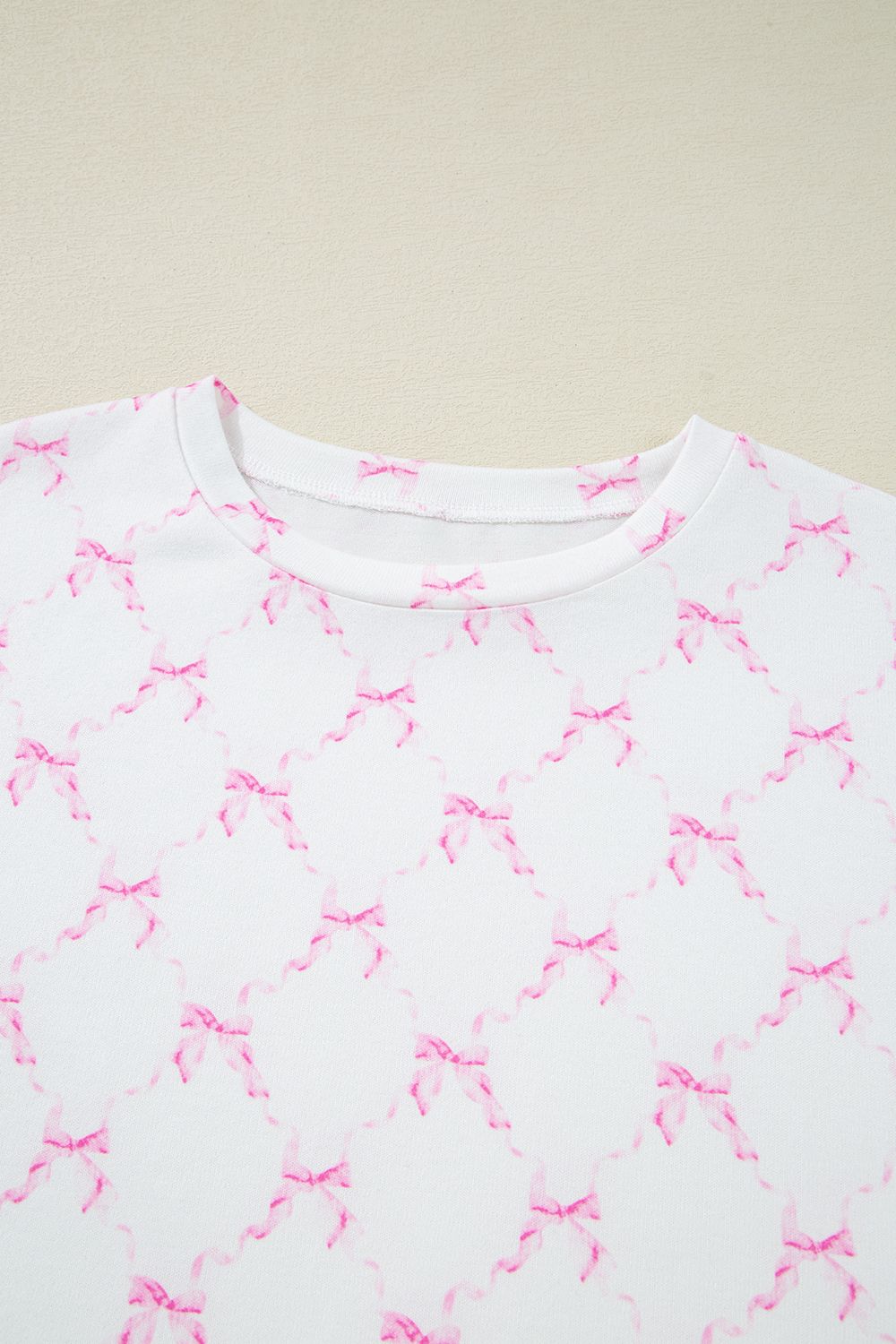 White loungewear set with pink bow print and scalloped edges.
