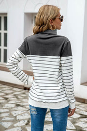 Colorblock stripe turtleneck knit sweater in dark gray and white with gray stripes.