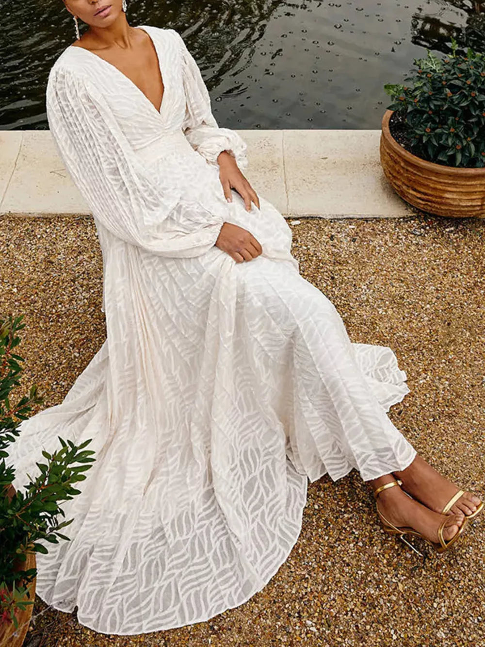 White maxi dress with V-neck, balloon sleeves, and leaf pattern fabric.