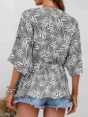 Black and white abstract print cinched waist blouse with 3/4 sleeves.