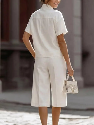 White two-piece set with pocketed top and wide-leg cropped pants, styled with a handbag.