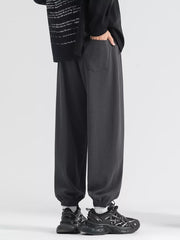 Men's dark gray loose fit sweatpants with drawstring and cuffed ankles.