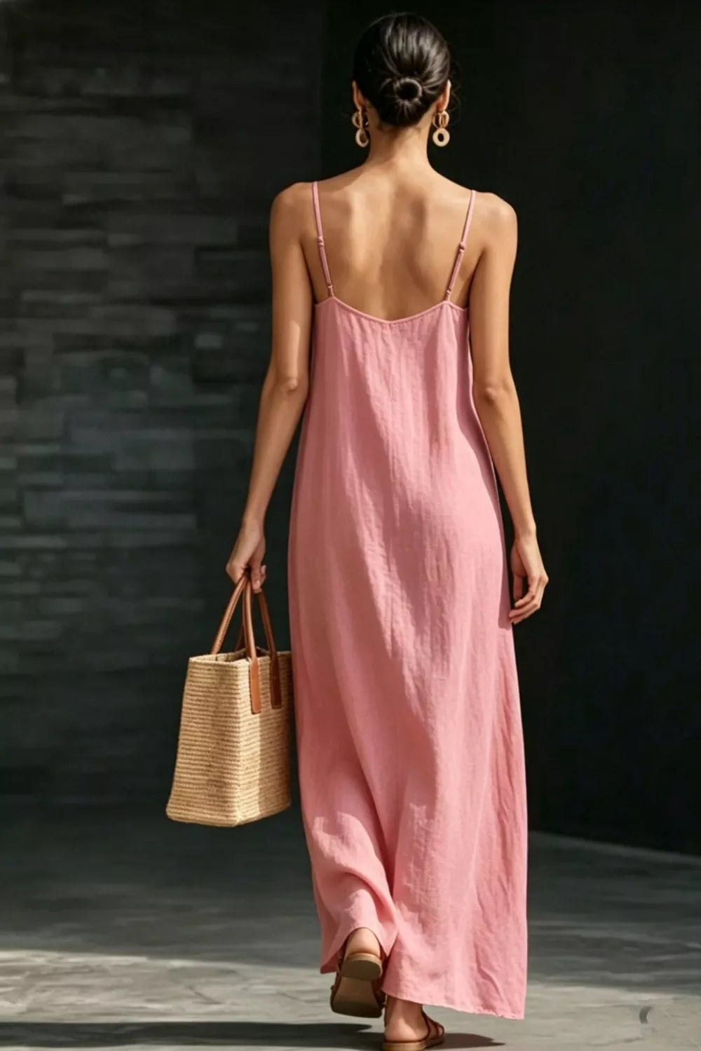 Dusty Pink V-neck maxi dress with spaghetti straps, flowing skirt, and straw tote bag.