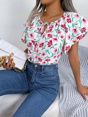 White floral ruffle sleeve tie-neck blouse with pink flowers and green leaves.