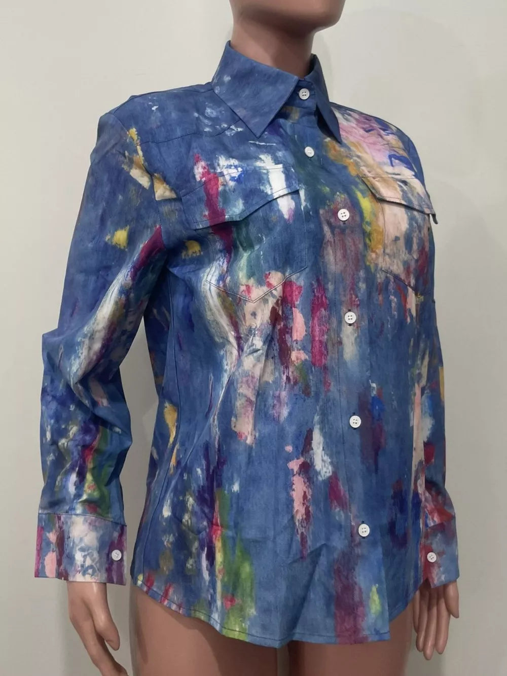 Denim button-up shirt with abstract colorful paint splatter pattern, long sleeves, and two chest pockets.