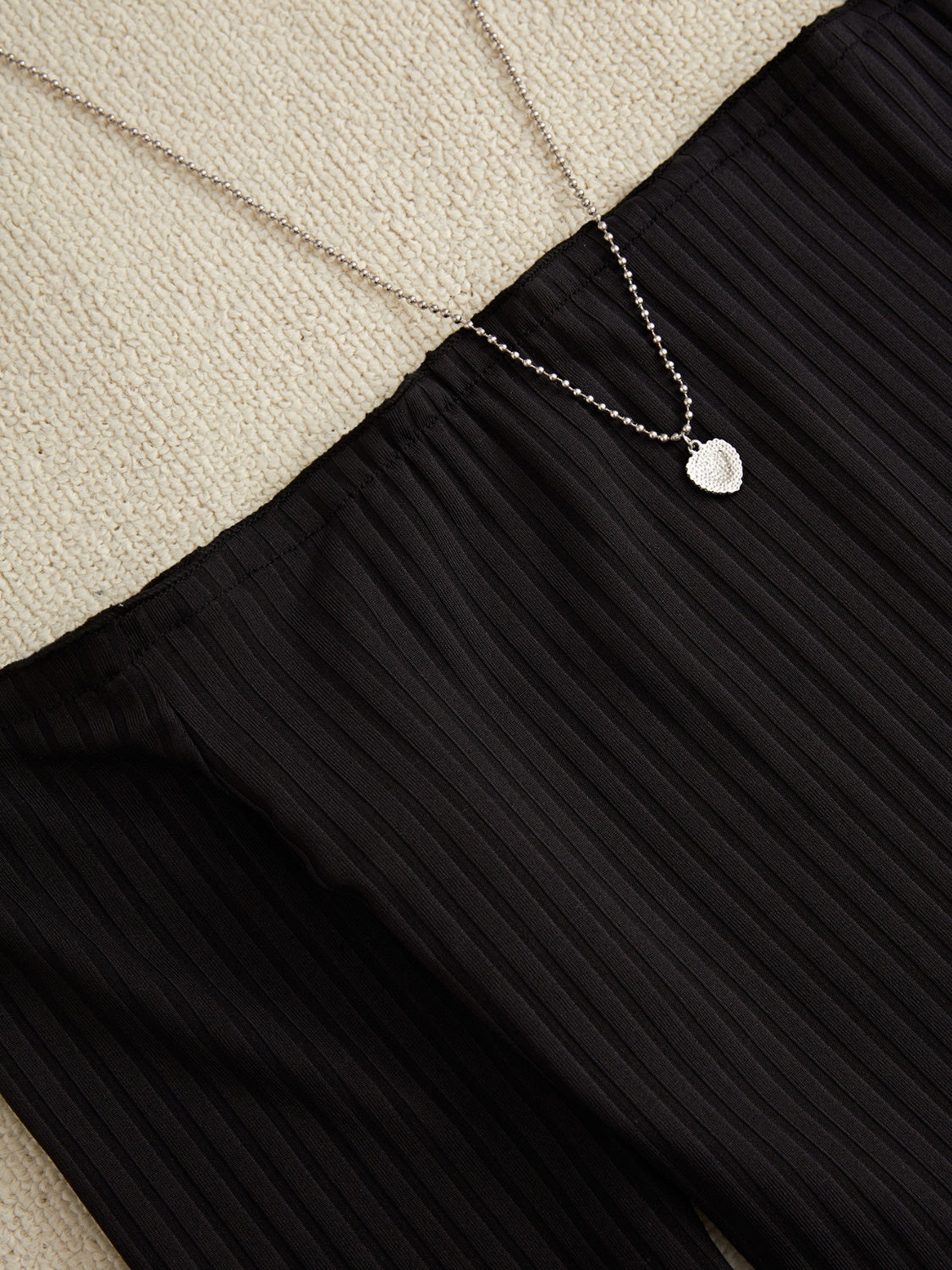 Black ribbed pencil skirt with a silver heart pendant necklace