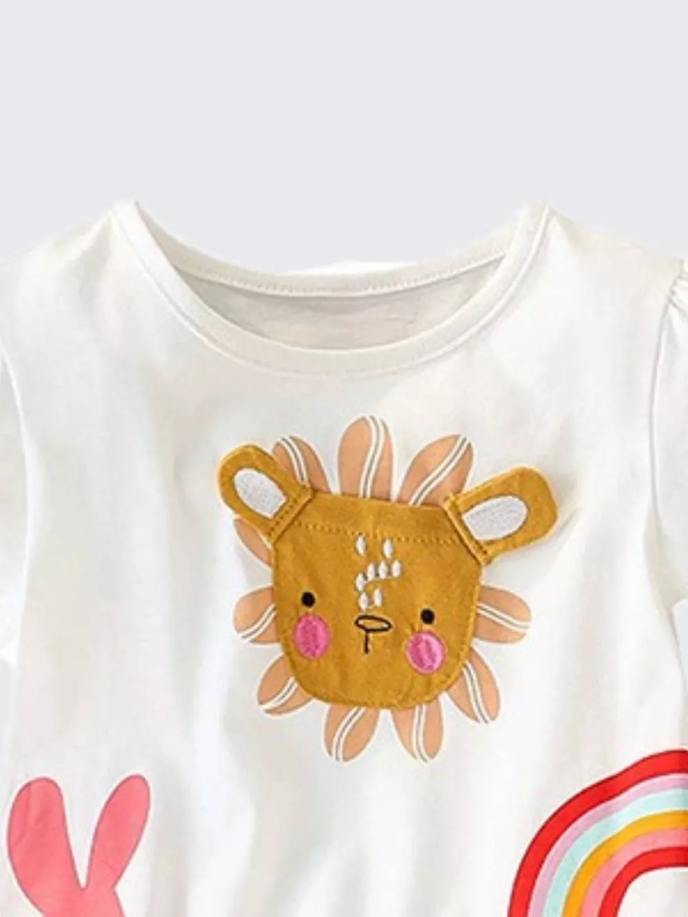 White cotton t-shirt with a playful lion face applique and rainbow detail.