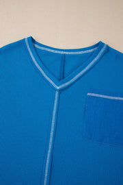 Blue waffle knit top with contrast stitching and lace paneled pocket detail.