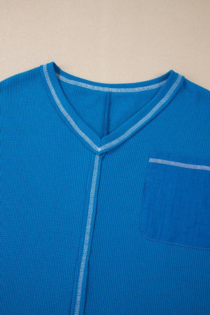 Blue waffle knit top with contrast stitching and lace paneled pocket detail.