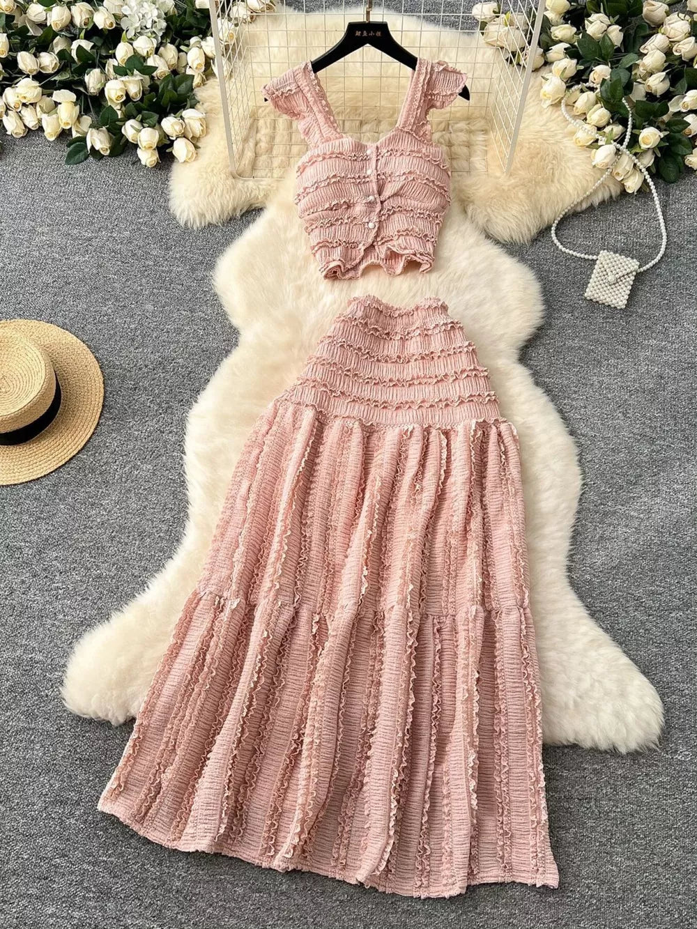 Pink textured ruffled two-piece set with buttoned crop top and tiered maxi skirt.