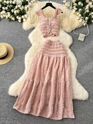 Pink textured ruffled two-piece set with buttoned crop top and tiered maxi skirt.