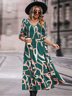 Midi dress in mid green with abstract print, smocked waist, V-neck, and tiered hem.