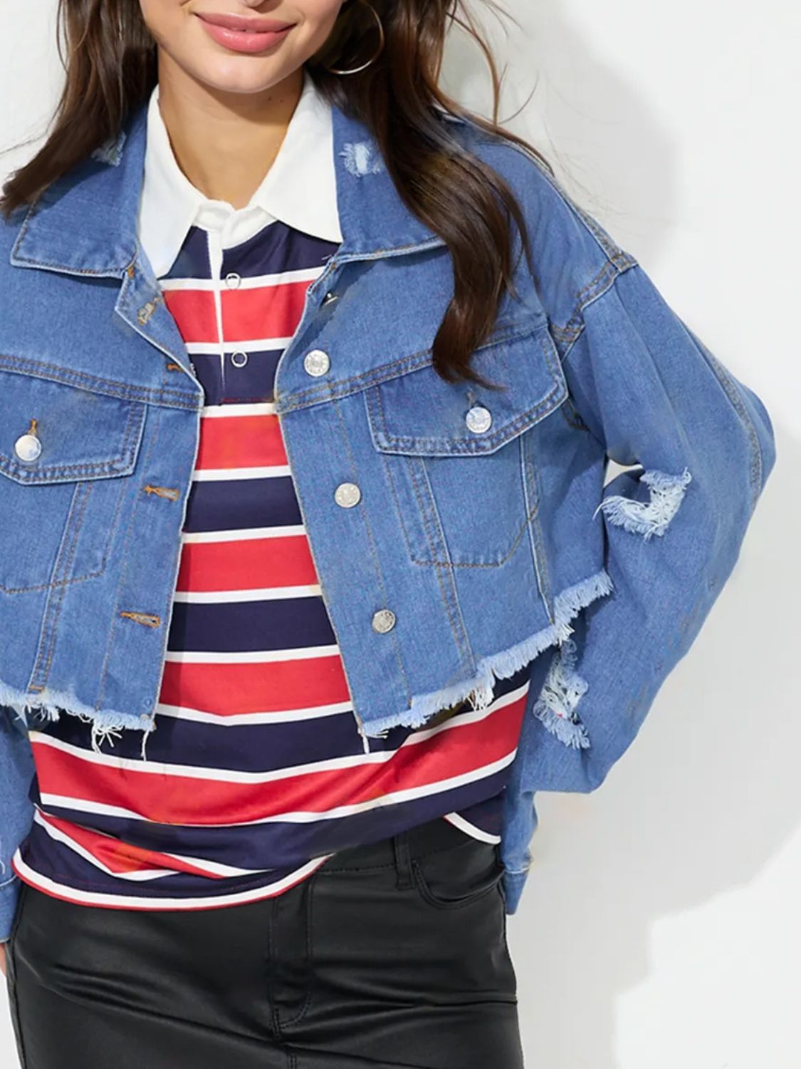 Medium wash denim trucker jacket with raw hem and distressed details.
