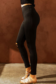 Black performance leggings with distressed knee slits and a high waist.