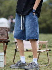 Relaxed fit blue denim shorts with white drawstring and pockets.