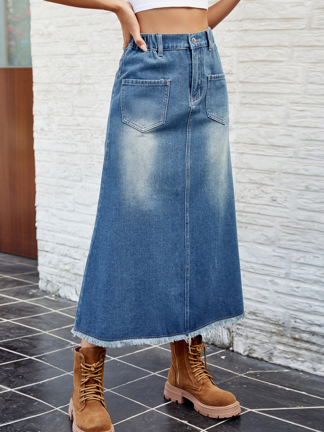 Faded blue denim midi skirt with frayed hem and front pockets.