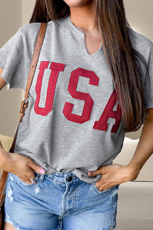Gray sweatshirt with red USA appliqué and notch neckline, styled with denim shorts.