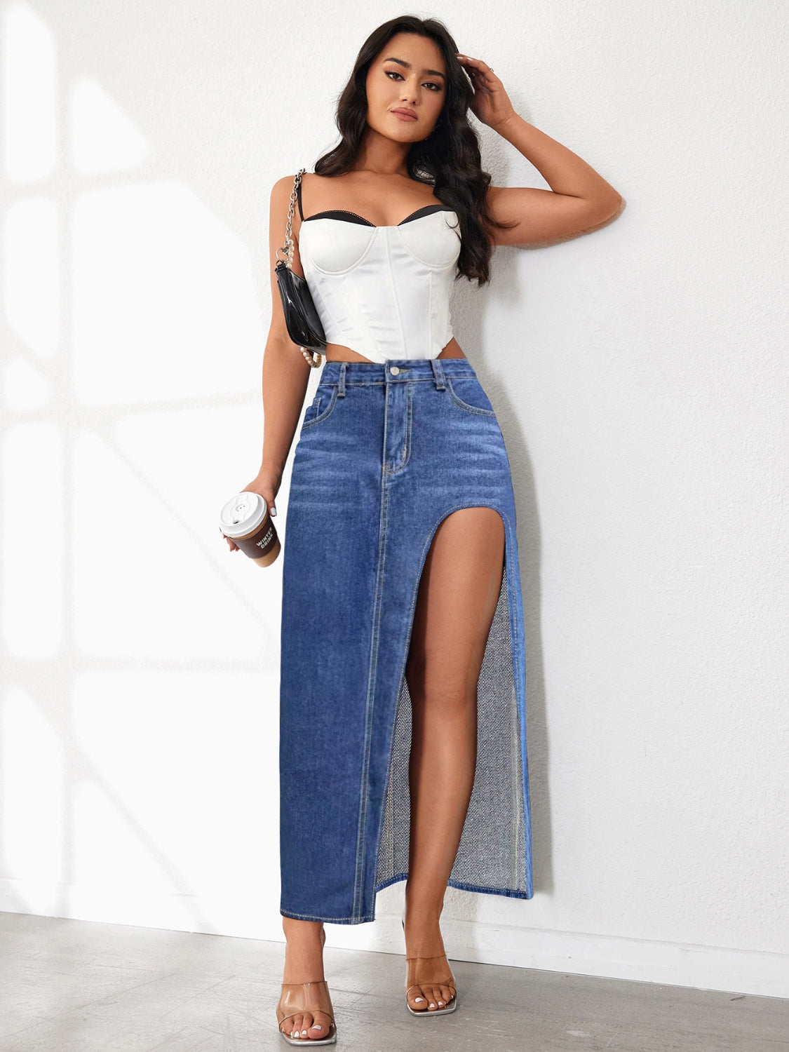 Light blue denim maxi skirt with a high slit, styled with a white corset top.