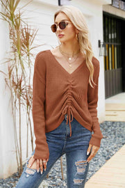 Brown waffle knit sweater with ruched front and tie detail, V-neck, long sleeves.