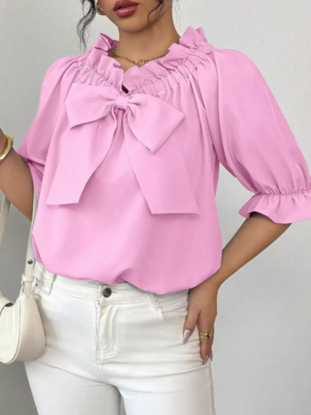 Pink ruffled bow blouse with puff sleeves and cinched neckline.