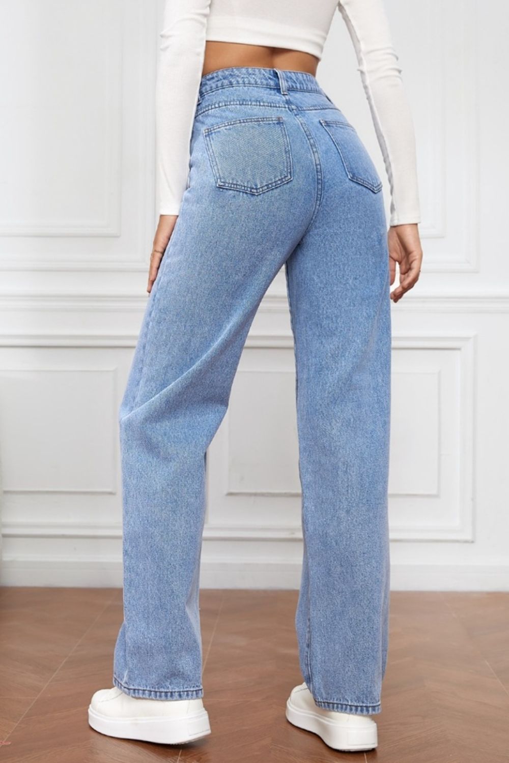 Light blue denim jeans with a wide leg and sculpted waist, shown from the back.