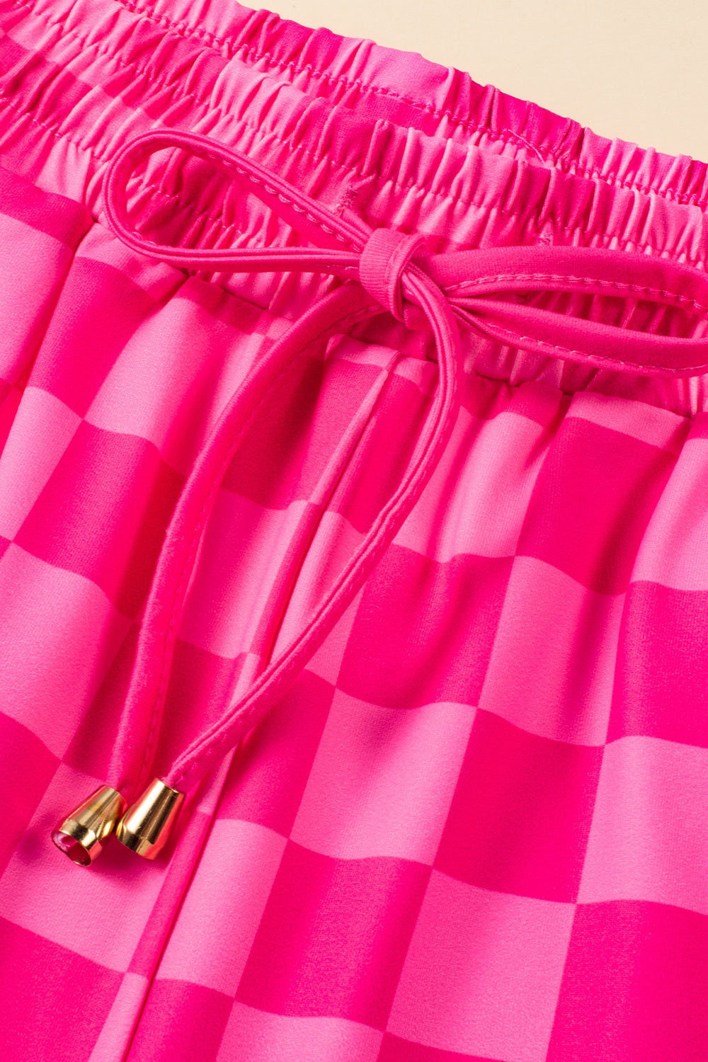 Hot pink checkered loungewear shorts with drawstring and gold tips.