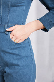 Denim utility jumpsuit in medium wash with defined waist and pocket detail.