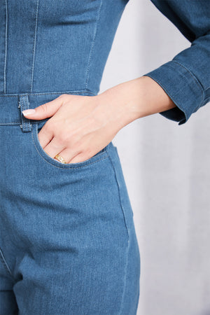 Denim utility jumpsuit in medium wash with defined waist and pocket detail.