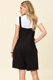 Black textured bib short romper with square neckline and adjustable straps.