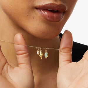 Gold necklace with pearl, conch shell, and gemstone charms.