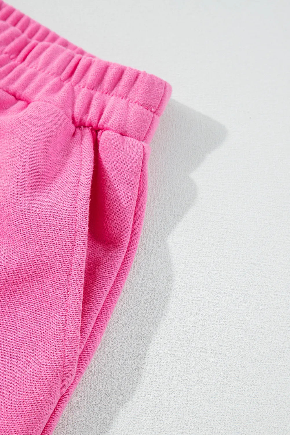 Fuchsia pink cotton loungewear pants with elastic waistband and side pocket detail.