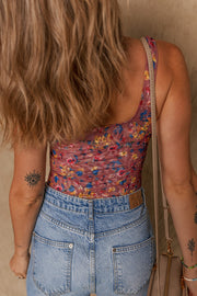Floral mesh bodysuit with scoop neck and colorful floral print, styled with denim.