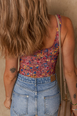 Floral mesh bodysuit with scoop neck and colorful floral print, styled with denim.
