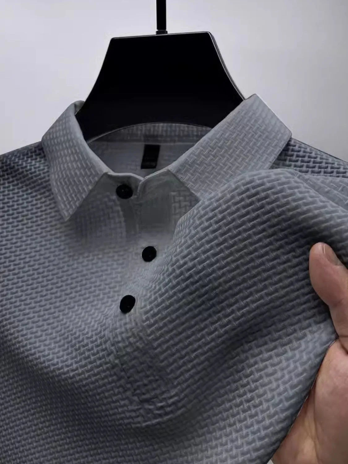 Gray textured weave polo shirt with maxi collar and black buttons, close-up detail.
