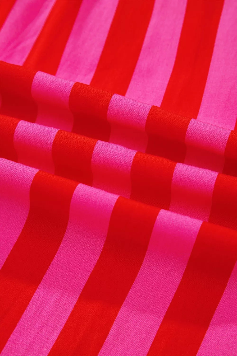Vibrant puff sleeve shirt in bold red and pink stripes, cotton blend fabric.