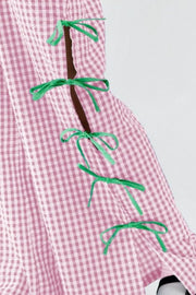 Blush pink gingham wide-leg trousers with green bow details on the side seam.