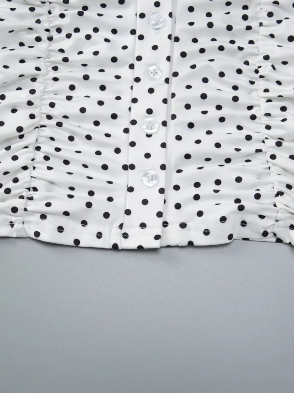 White polka dot t-shirt with ruched sides and button front detail.