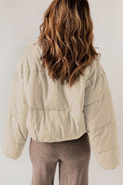 Cream cropped puffer jacket with hooded collar and horizontal quilting.