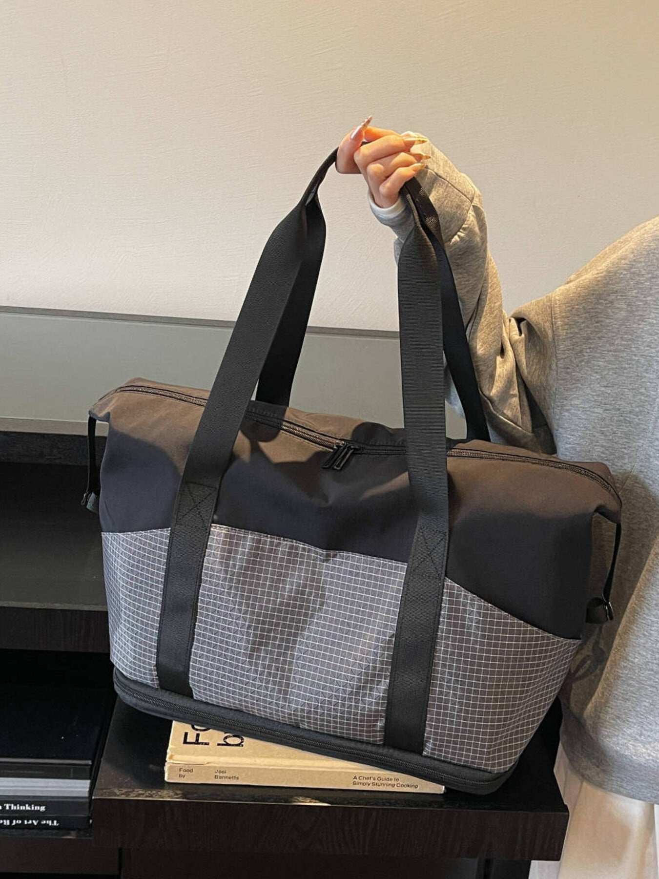 Black nylon travel duffel bag with checkered side panels and black straps.