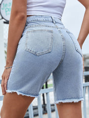 Distressed light wash denim bermuda shorts with frayed hem and chain detail.