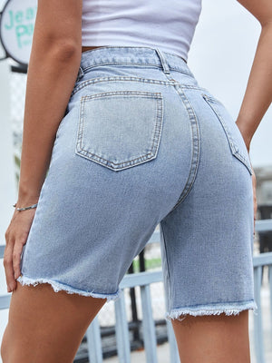 Distressed light wash denim bermuda shorts with frayed hem and chain detail.