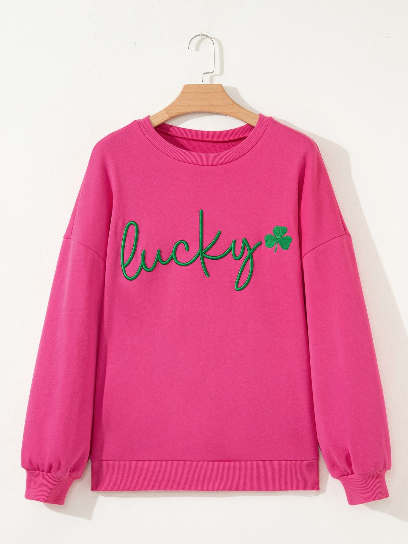 Pink crew neck sweatshirt with green embroidered lucky clover graphic