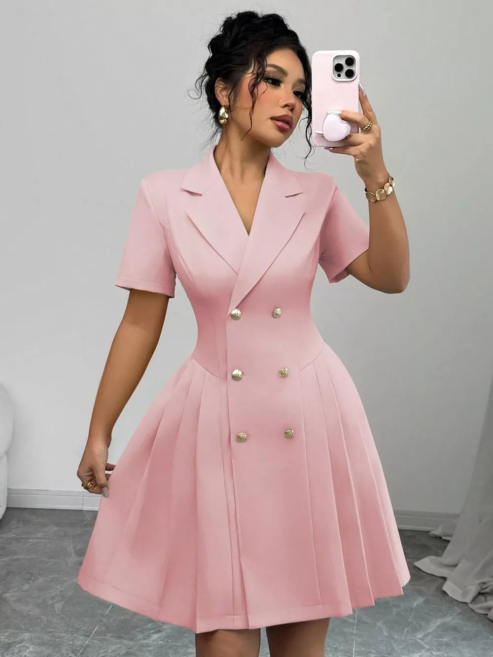 Blush pink double-breasted pleated blazer dress with gold buttons and short sleeves.