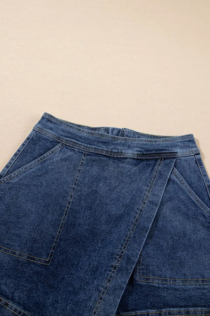Denim wrap skort in medium wash with asymmetrical hem and patch pockets.