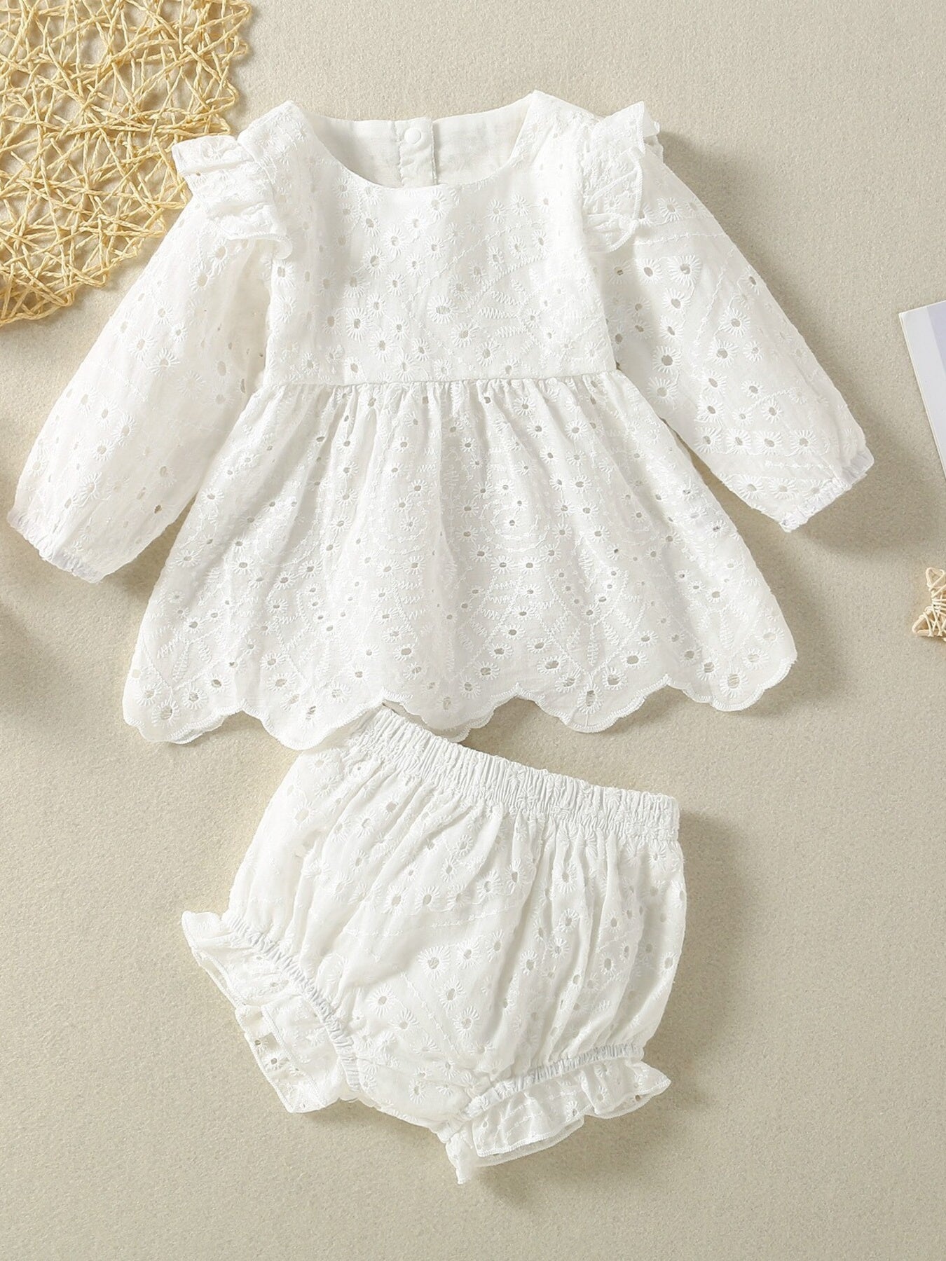 White cotton embroidered lace baby top with ruffled sleeves and scalloped hem, paired with bloomers.