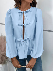 Light blue peplum blouse with keyhole neckline and bow details, long puff sleeves.