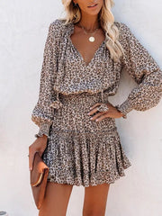 Leopard print tiered mini dress with ruffled neckline and smocked waist.